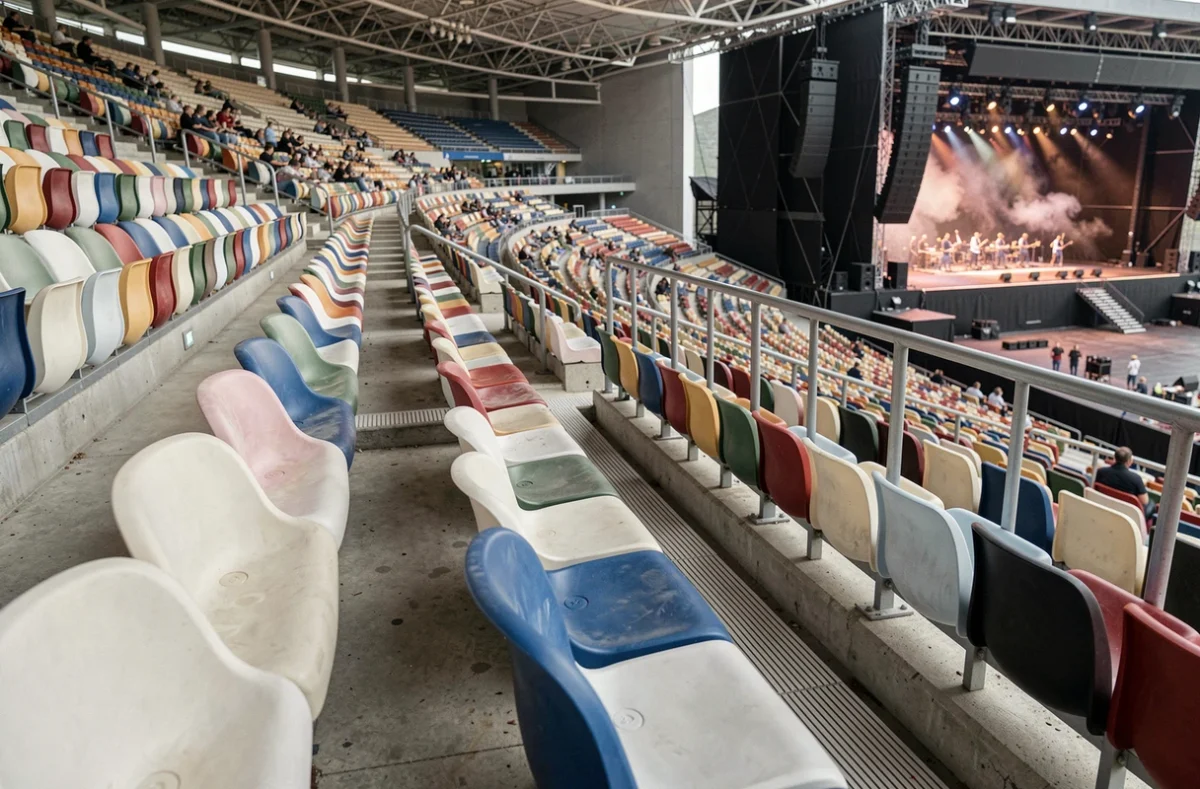 Rangées de sièges en gradin supérieur du Stade de France avec vue sur la scène et les enceintes, zones d'écoute acoustique en concert